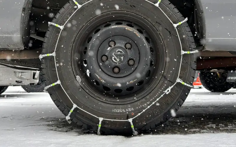 Sneeuwketting om een autoband in de sneeuw